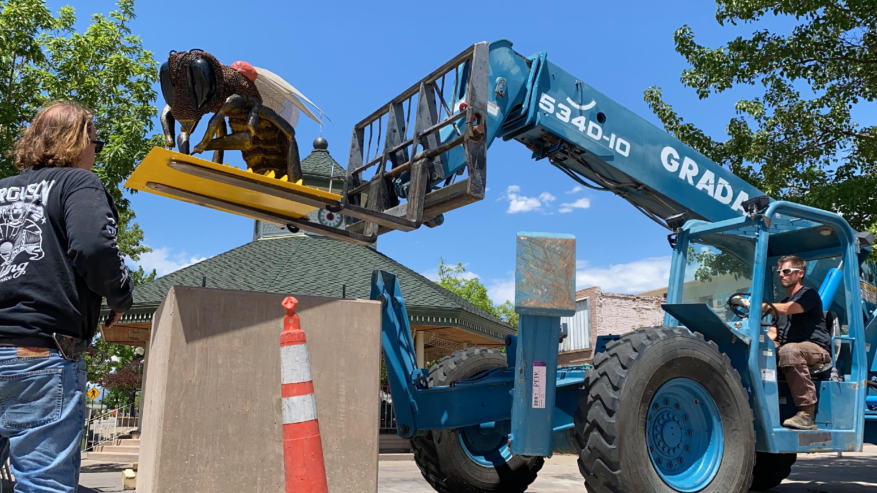 A man stands beside a blue crane