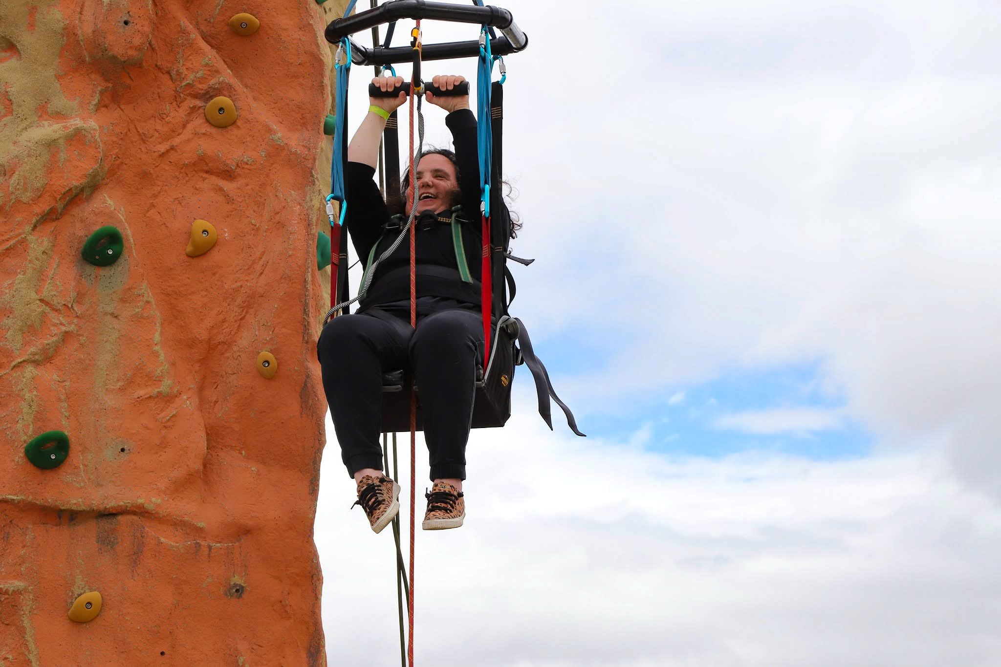Woman using adaptive rock climbing equipment at the Mark Wellman Adventure Day event. 